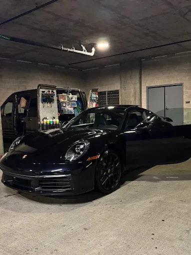 Black Porsche 911 polished in the detailing bay beside the mobile setup